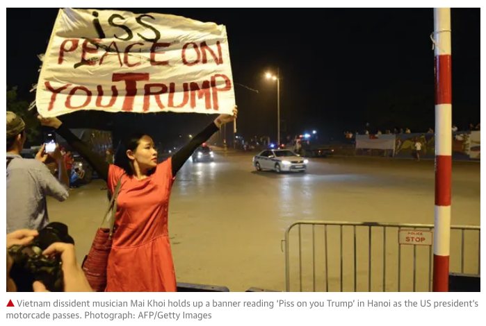 Vietnam dissident musician Mai Khoi holds up a banner reading ‘Piss on you Trump’ in Hanoi as the US president’s motorcade passes. Credit AFP-Getty Images